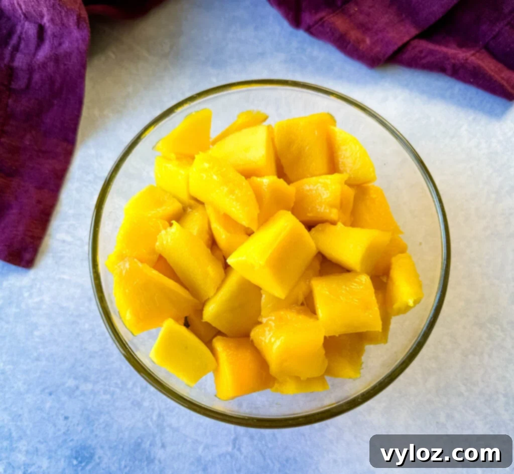 Tropical Mango Medley with Zesty Lime Honey Dressing 3 Close-up of freshly diced ripe mango chunks in a clear glass bowl, showcasing their bright orange color and juicy texture.
