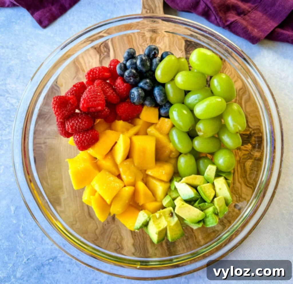 Tropical Mango Medley with Zesty Lime Honey Dressing 6 A vibrant mix of raspberries, blueberries, grapes, and avocado, fresh and ready, combined in a clear glass bowl before the dressing is added.