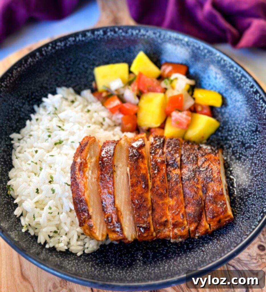 Blackened Chicken 2 blackened chicken breasts with rice and mango salsa in a black bowl