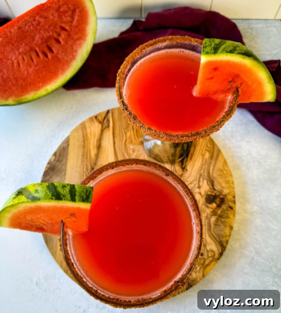 watermelon margaritas on the rocks in a glass with Tajin lined rim and fresh watermelon