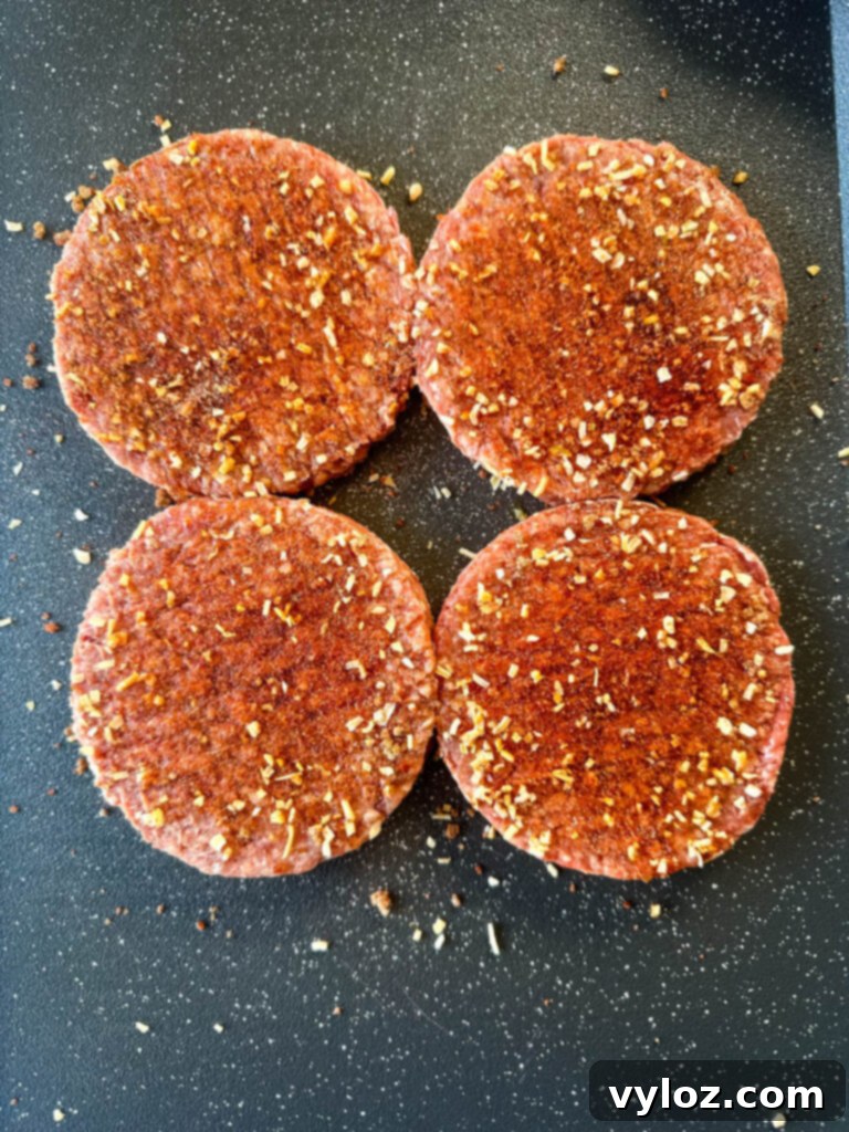 raw seasoned burgers on a flat surface