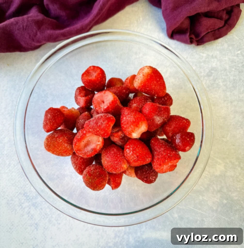 Frozen strawberries in a clear glass bowl, ready for blending.