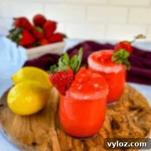 Close-up of frozen strawberry lemonade in a glass, garnished with fresh fruit, showcasing its appealing texture and color.