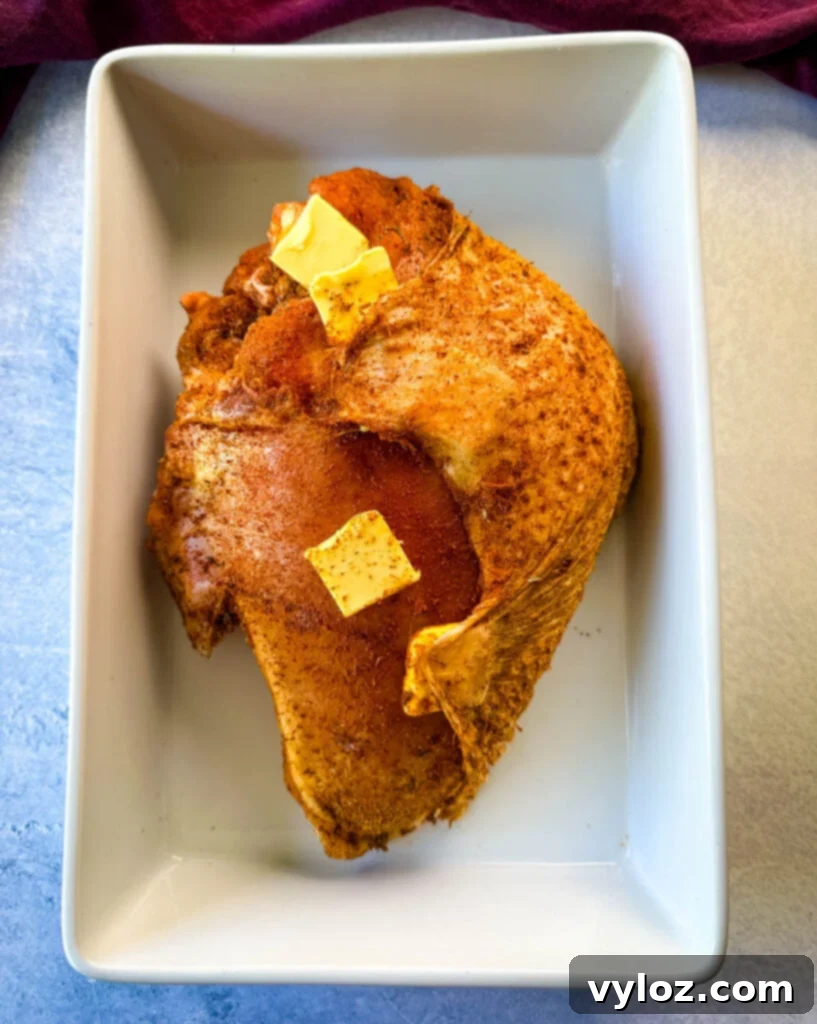 Juicy Bone-In Turkey Breast 6 raw seasoned bone in turkey breast topped with butter in a white 9x13 baking dish