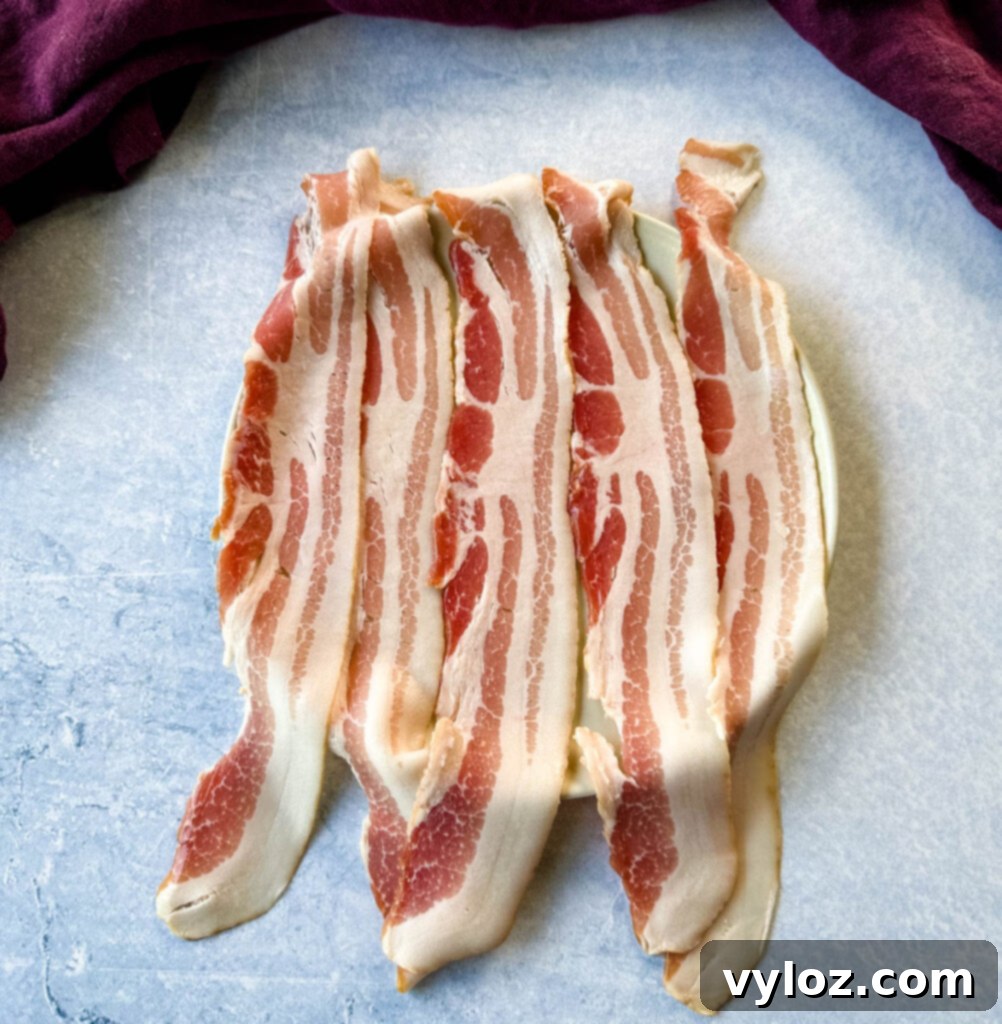 5 slices of uncooked bacon on a plate