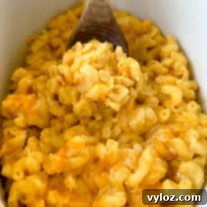 Effortless Crockpot Mac and Cheese 9 cheddar cheese mac and cheese in a Crockpot slow cooker with a wooden spoon