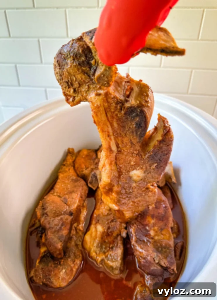 country style ribs falling off the bone of a pair of tongs