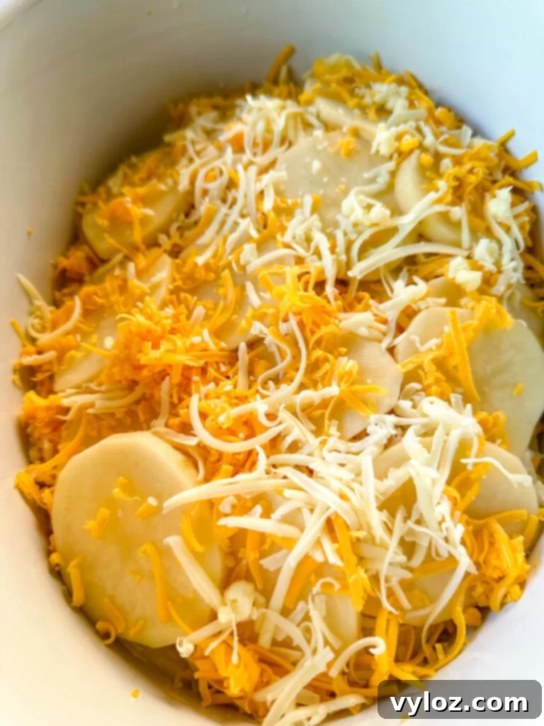 uncooked slow cooker cheesy potatoes in a white Crockpot