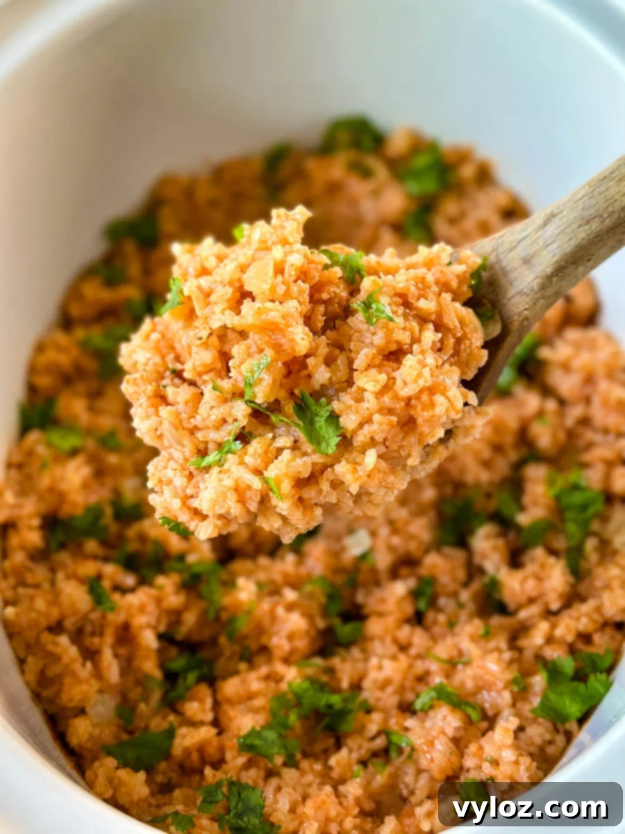 cooked Spanish Mexican rice in a white slow cooker Crockpot with a wooden spoon