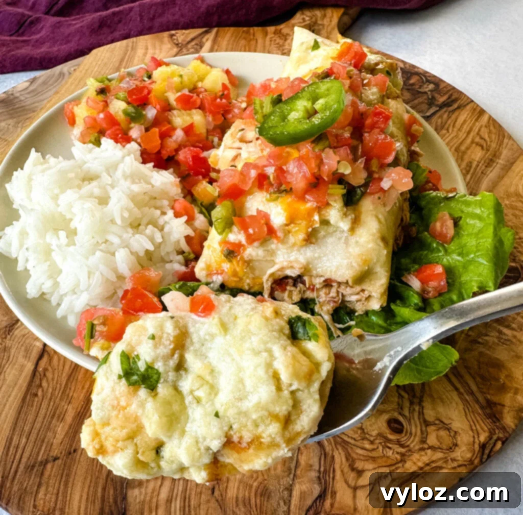a spoonful of rotisserie chicken enchiladas on a plate with pico de gallo and jalapenos