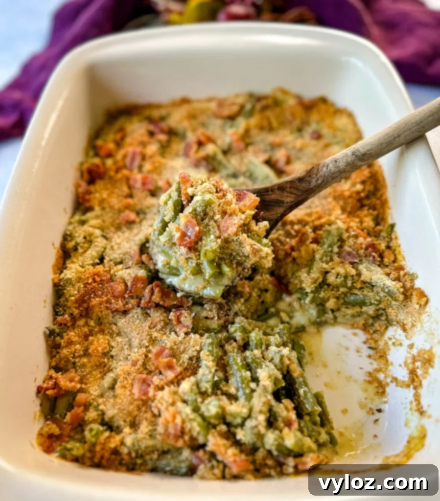 A baked green bean casserole with bacon and breadcrumbs in a baking dish, ready to be served