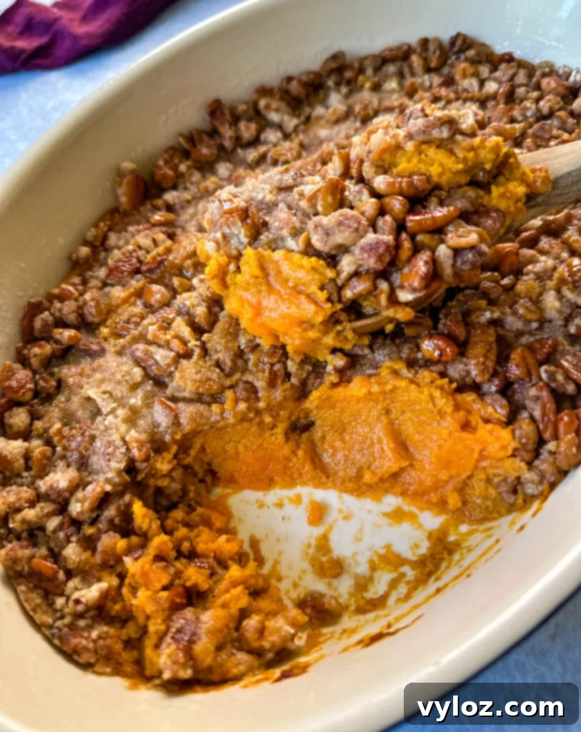 Golden Sweet Potato Pecan Delight 12 Close-up of a sweet potato casserole with pecan topping in a baking dish, ready to be served.