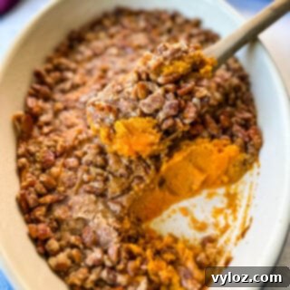 Golden Sweet Potato Pecan Delight 13 Sweet potato casserole with pecans in a baking dish with a wooden spoon for serving.