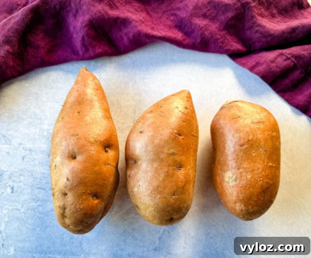 Golden Sweet Potato Pecan Delight 4 Raw, unpeeled sweet potatoes on a rustic wooden surface, ready for preparation.