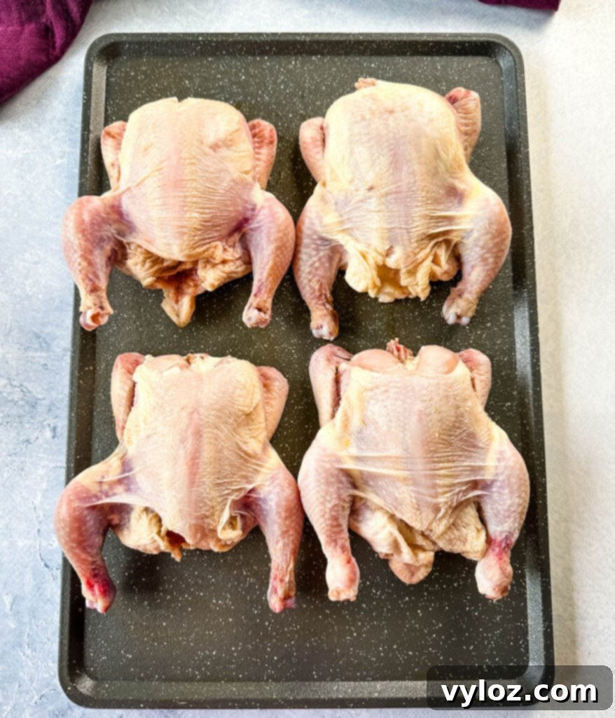 raw Cornish hens on a sheet pan