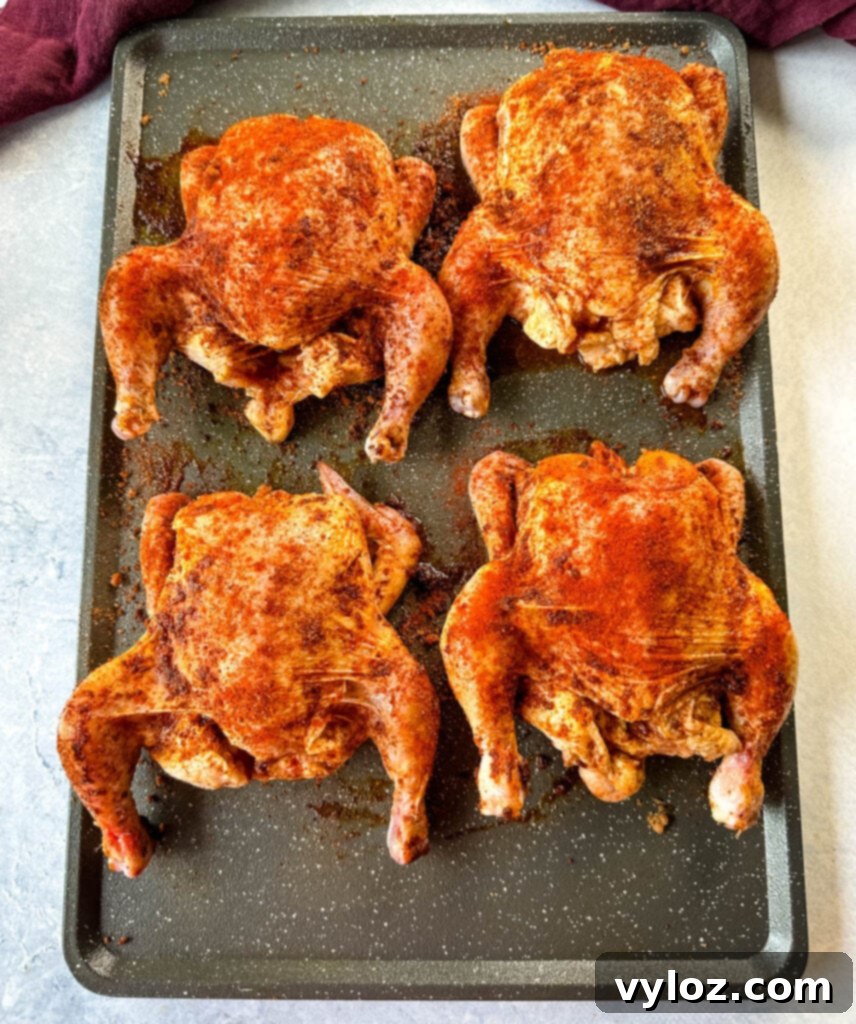 raw seasoned Cornish hens on a sheet pan