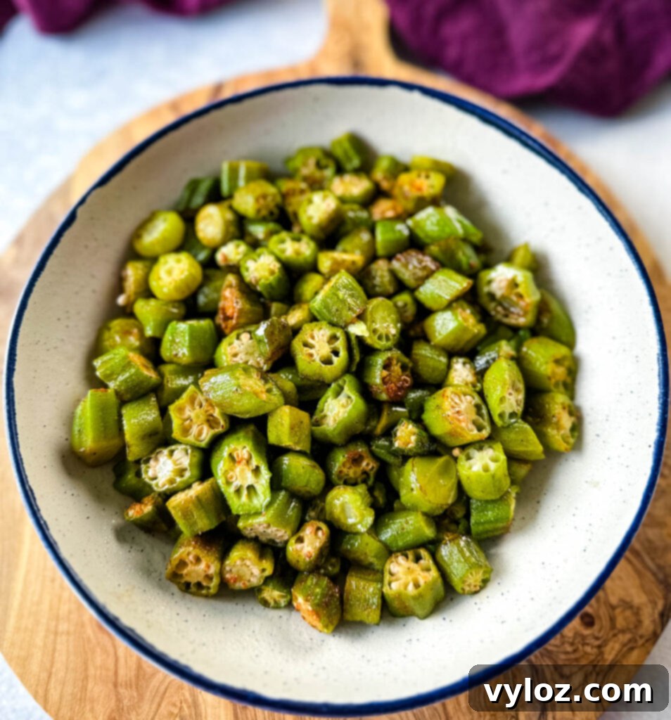 A vibrant close-up of roasted okra seasoned to perfection in a white bowl