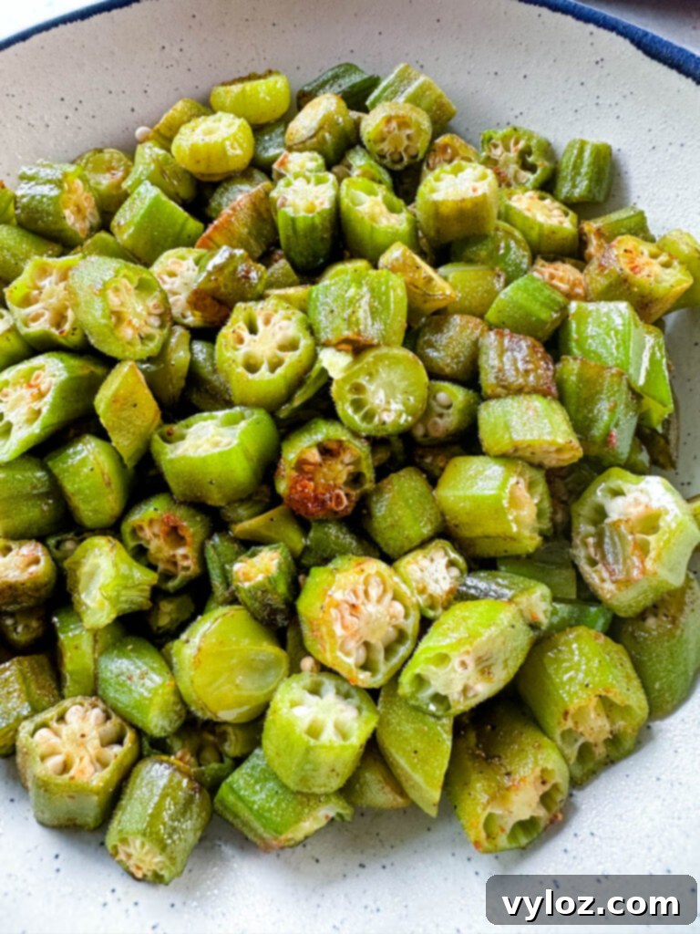 A serving of roasted okra in a white ceramic bowl, garnished lightly
