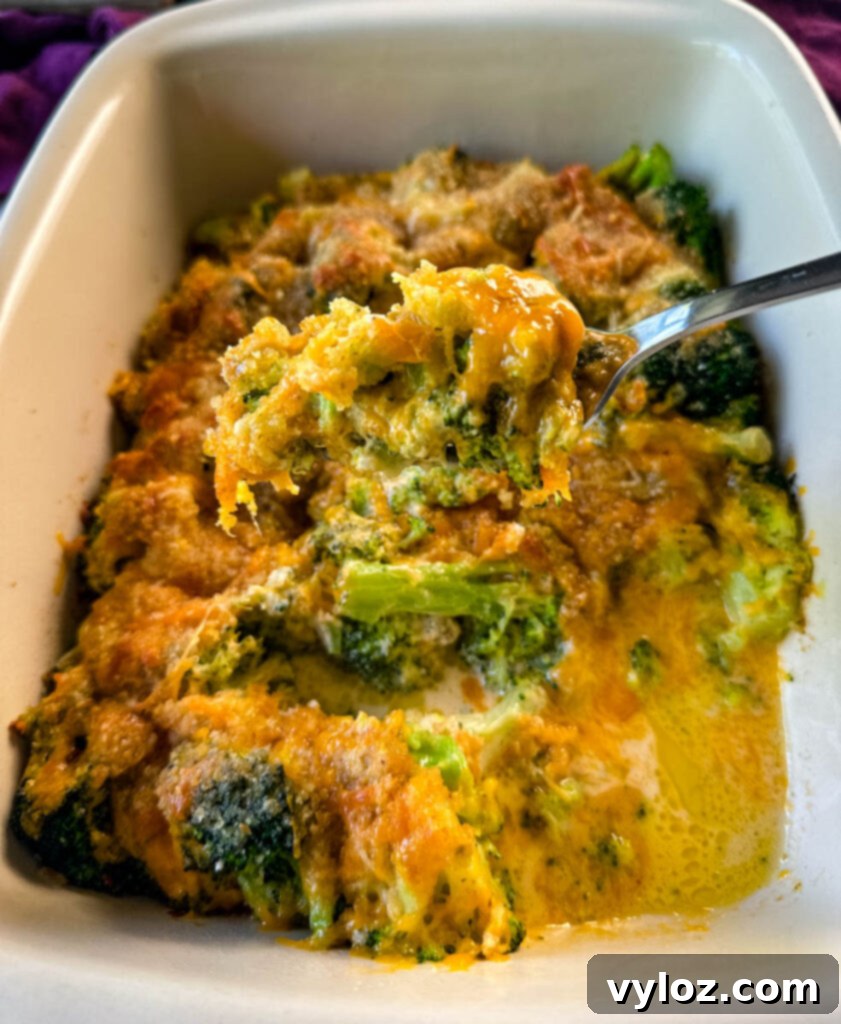 a fork full of broccoli au gratin with cheese and breadcrumbs in a baking dish