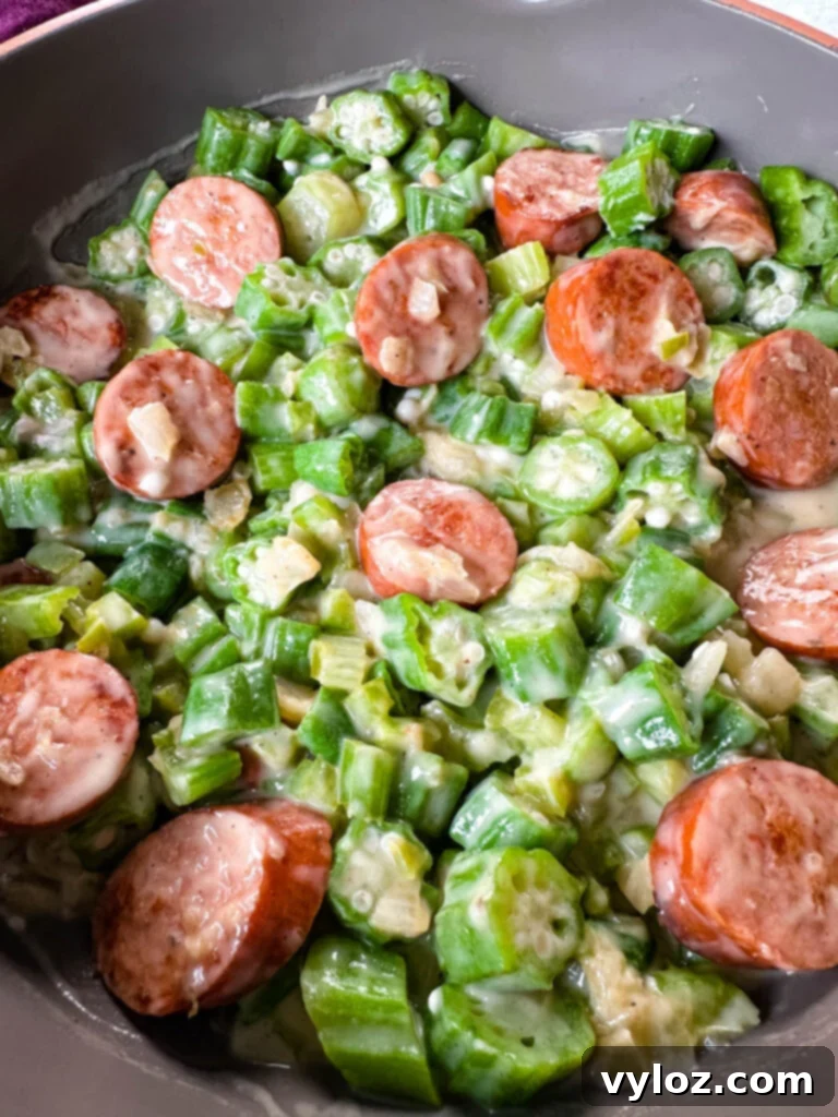 Smothered okra with sausage and gravy in a skillet, served hot