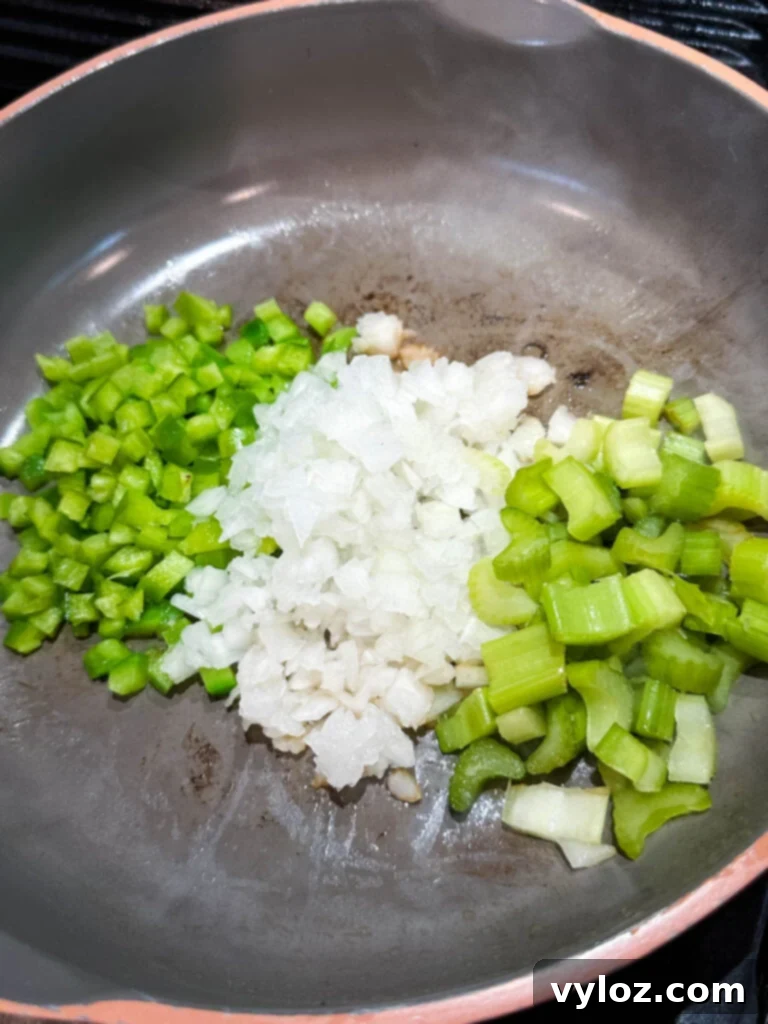Sautéed green bell peppers, onions, and celery in a skillet