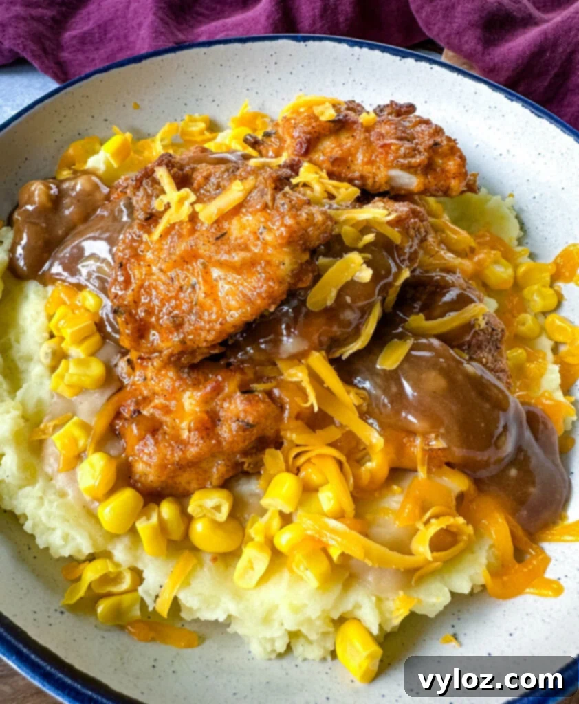 A delicious and satisfying homemade KFC Famous Bowl featuring crispy chicken, creamy mashed potatoes, sweet corn, savory gravy, and melted shredded cheese.