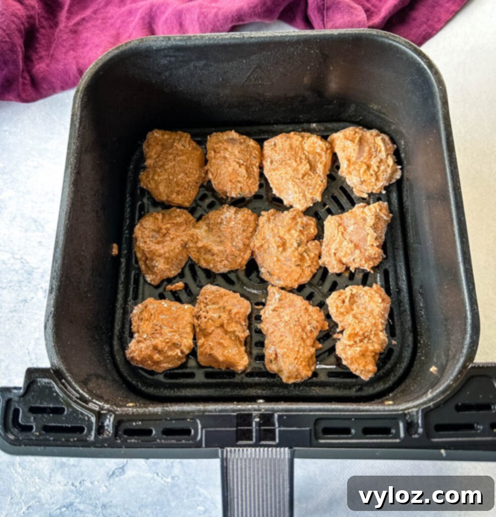 Uncooked, breaded chicken tenderloins arranged neatly in an air fryer basket, ready for cooking.