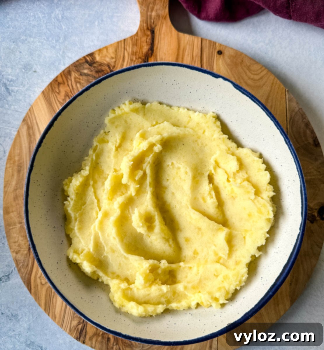 A white bowl brimming with fluffy, creamy mashed potatoes, ready to be topped.