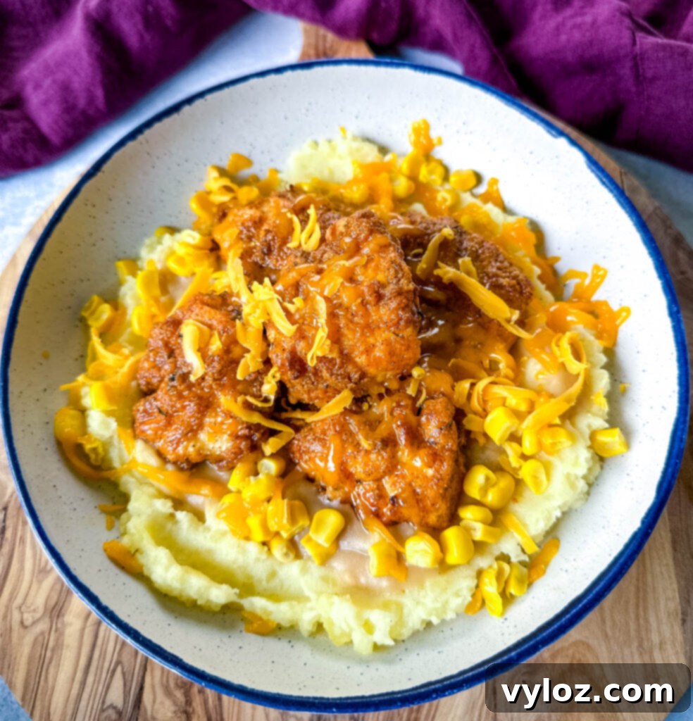 A beautifully presented homemade KFC Famous Bowl, layered with crispy chicken, mashed potatoes, gravy, and melted cheese, ready to be enjoyed.