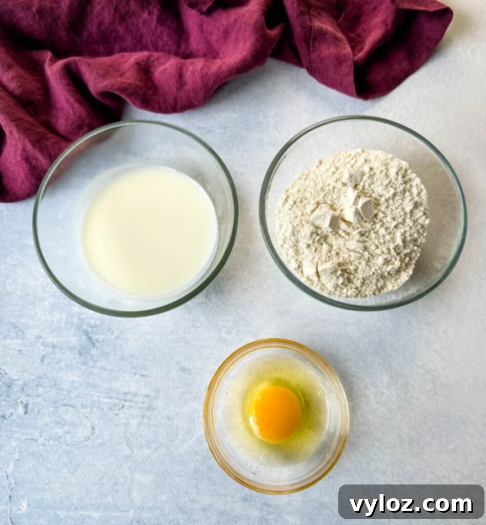 Separate glass bowls containing buttermilk, all-purpose flour, and a whisked egg, laid out for the chicken breading process.