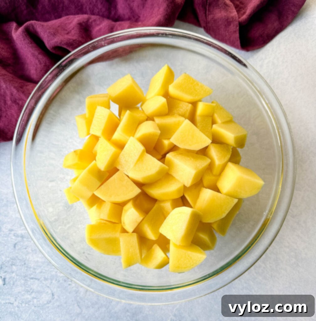 Peeled and cut potatoes resting in a clear glass bowl, prepped for mashing.