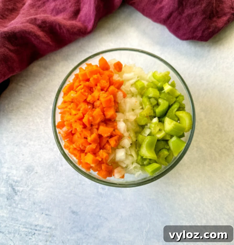diced carrots, celery, and white onions in a glass bowl