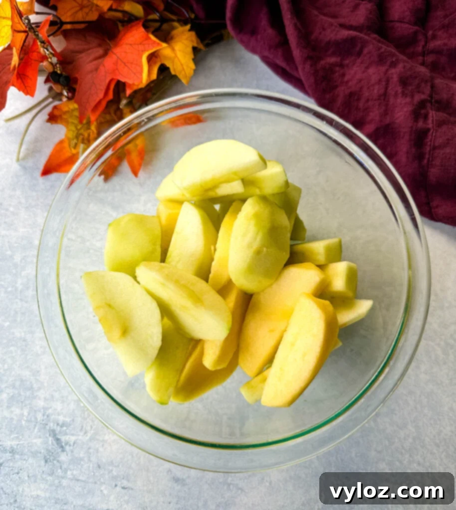 Down-Home Fried Apples 5 Granny Smith apples in a clear glass bowl, showcasing their vibrant green color.