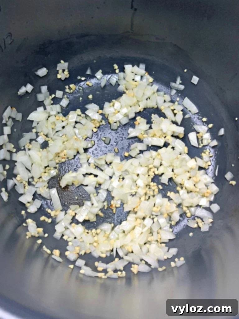 No-Stir Creamy Instant Pot Shrimp Risotto 5 Sautéed garlic and onions cooking inside an Instant Pot.