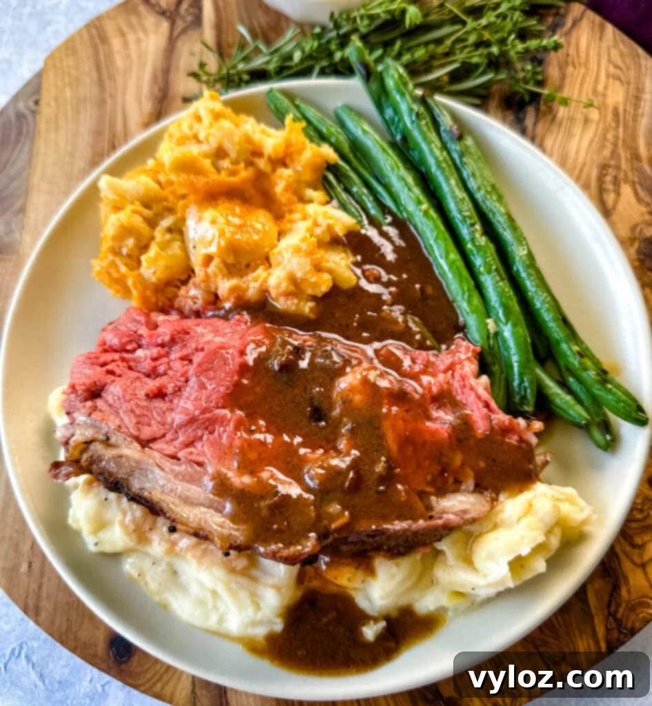 Bone-in or Boneless Garlic Butter Prime Rib 17 garlic herb butter roasted prime rib with au jus gravy on a plate with green beans, mashed potatoes, and mac and cheese