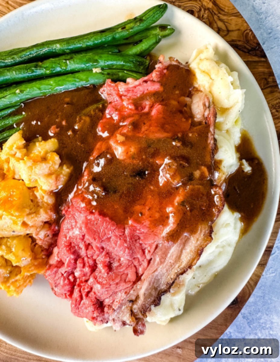 Bone-in or Boneless Garlic Butter Prime Rib 18 garlic herb butter roasted prime rib with au jus gravy on a plate with green beans, mashed potatoes, and mac and cheese