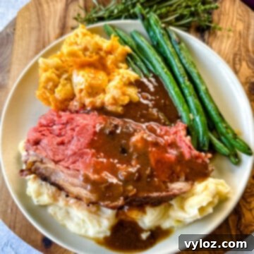 Bone-in or Boneless Garlic Butter Prime Rib 19 garlic herb butter roasted prime rib with au jus gravy on a plate with green beans, mashed potatoes, and mac and cheese