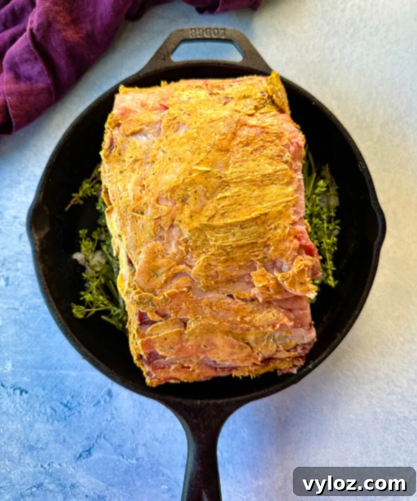 Bone-in or Boneless Garlic Butter Prime Rib 9 uncooked garlic herb butter roasted prime rib in a cast iron skillet with herbs