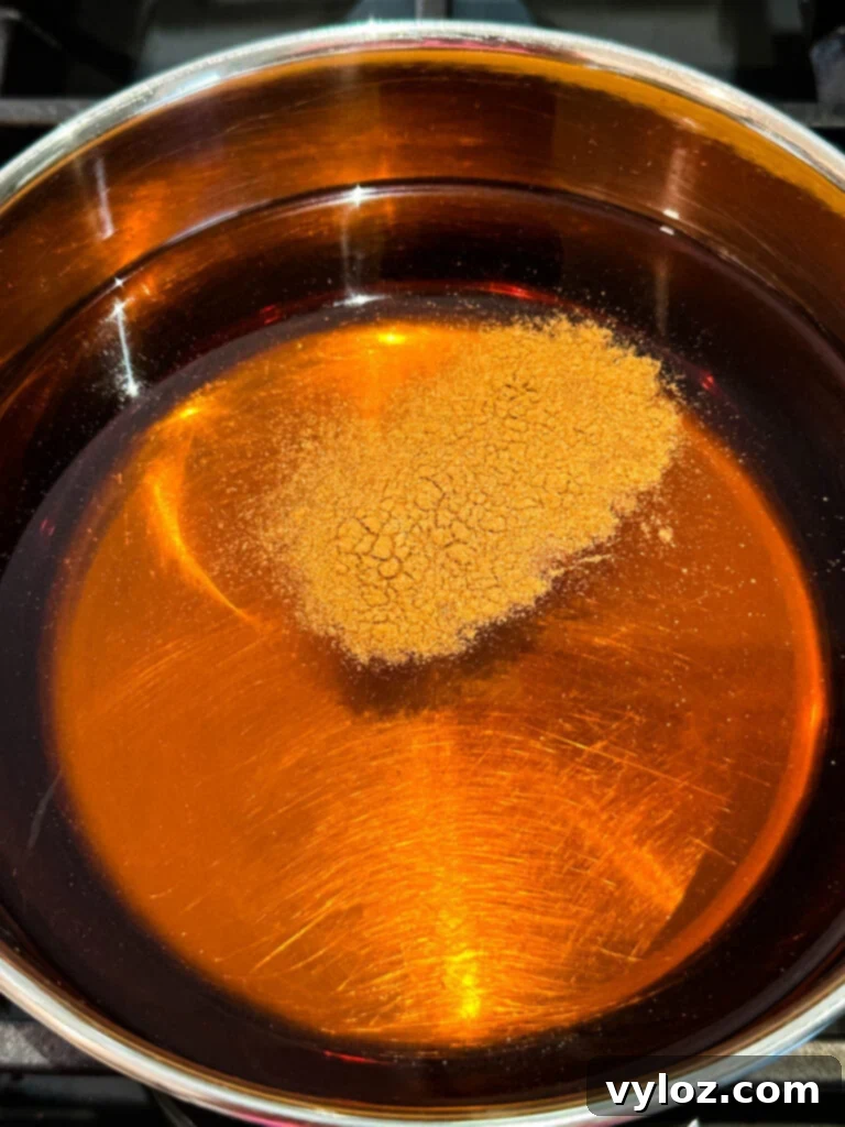 Bourbon, apple cider, and cinnamon sticks simmering in a saucepan
