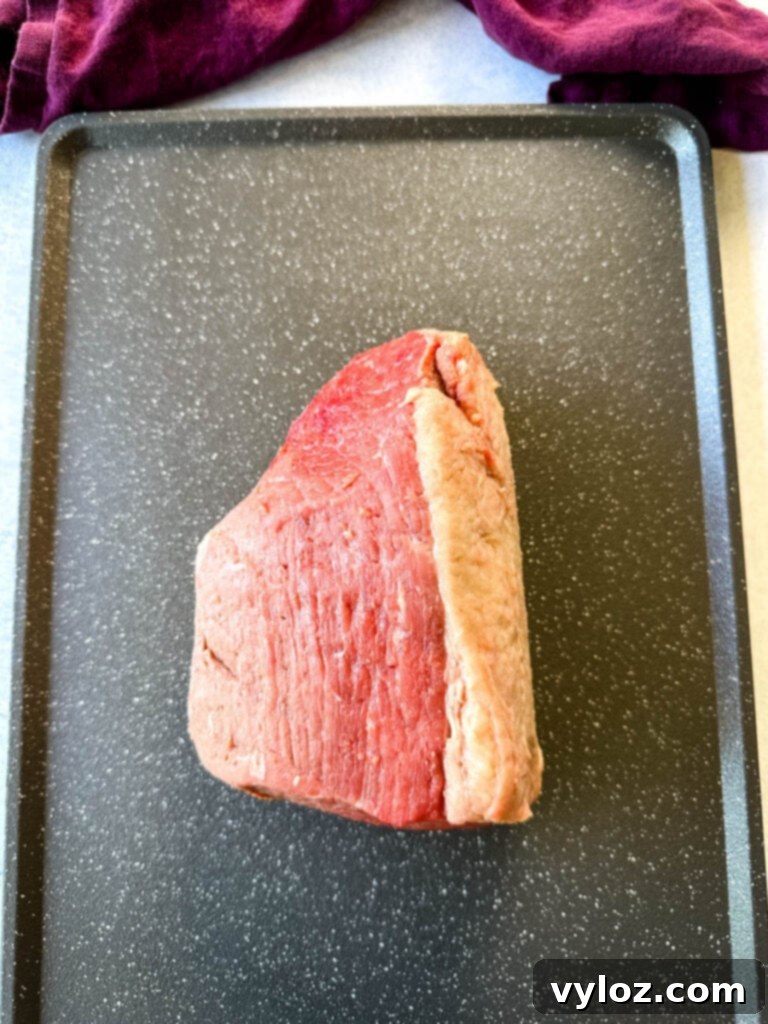 raw eye of round roast beef on a sheet pan