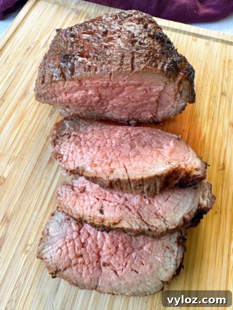 air fryer roast beef sliced on a bamboo cutting board