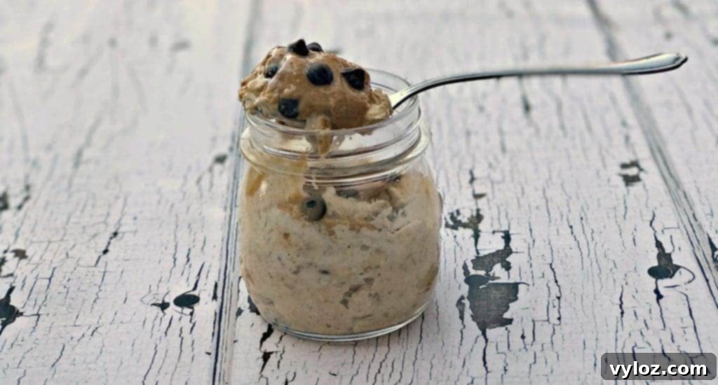 Two glass jars of Chocolate Chip Cookie Dough Protein Overnight Oats, garnished with extra chocolate chips and a spoon, ready to eat.