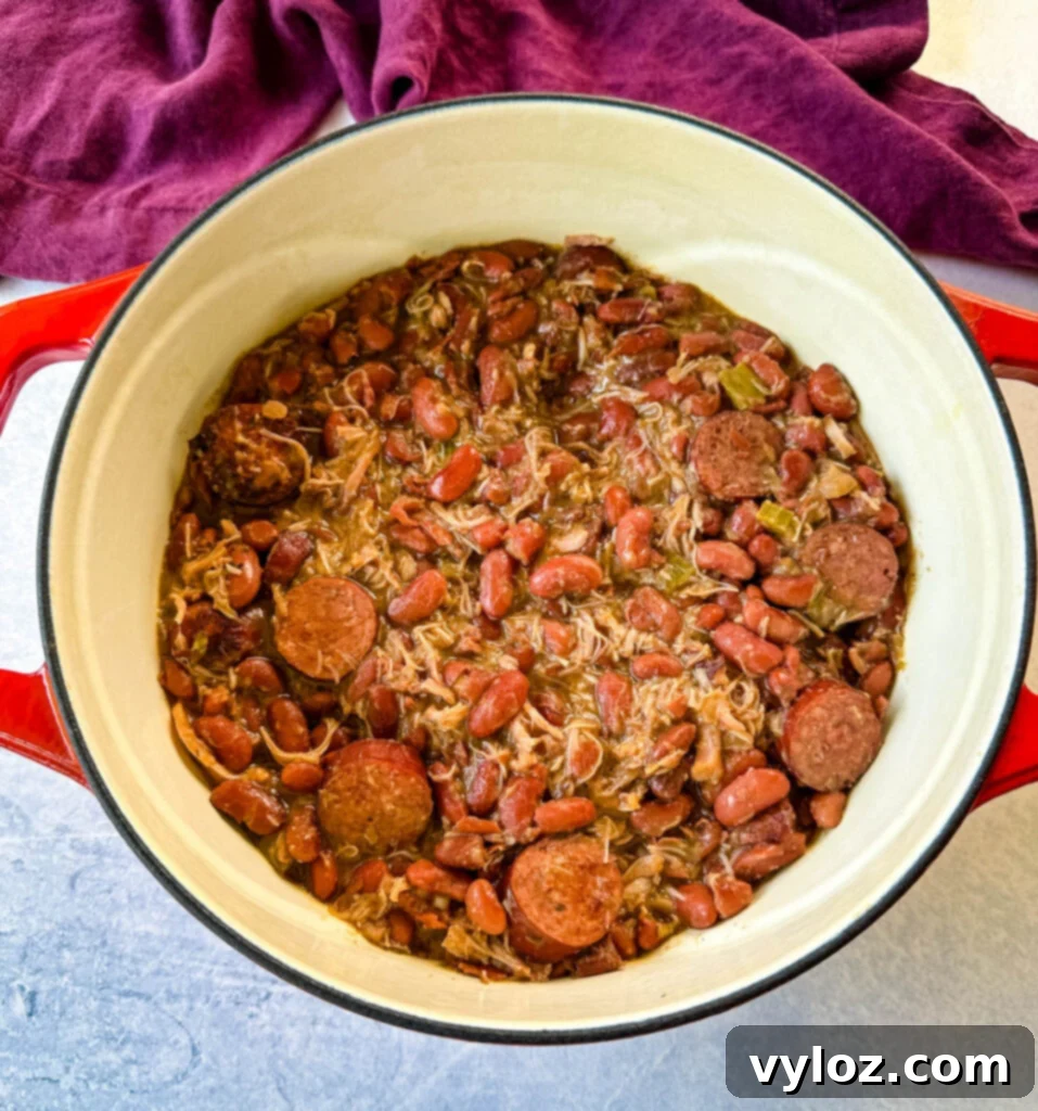 A large Dutch oven brimming with Southern Cajun red beans and rice, perfectly cooked with tender smoked turkey, showcasing the rich, comforting texture of the dish.