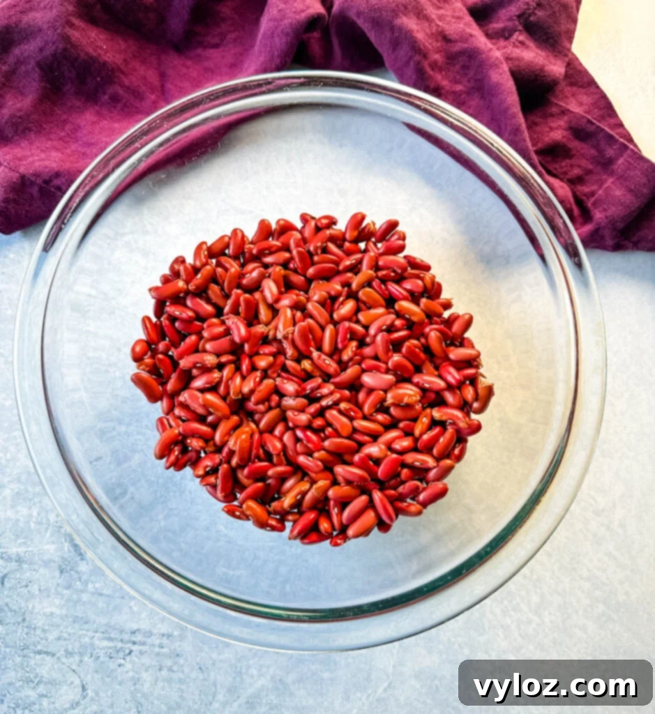 Dry red kidney beans in a clear glass bowl, showcasing their vibrant color and readiness for soaking and cooking.