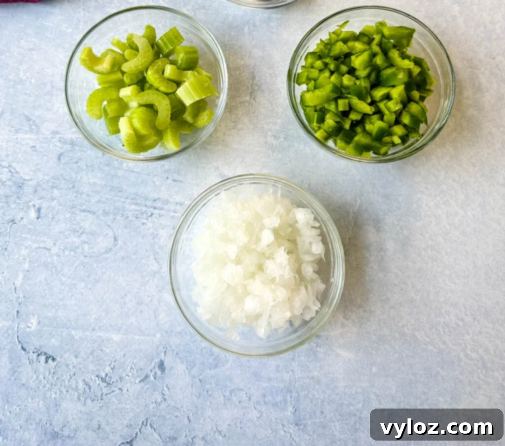 Separated bowls featuring freshly sliced green bell peppers, chopped celery, and diced onions – the quintessential 'Holy Trinity' of Cajun and Creole cooking.