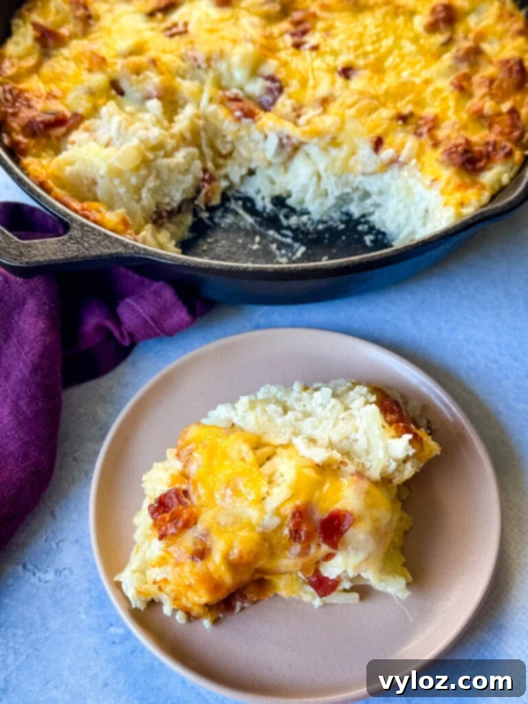 A serving of hash brown casserole with bacon and cheese on a white plate, garnished with fresh herbs.