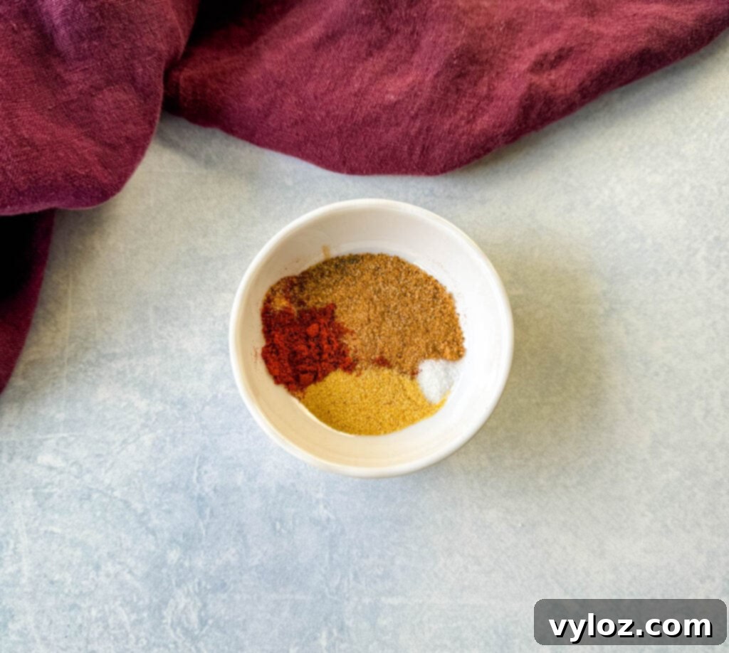 Three white bowls containing essential spices: aromatic Creole seasoning, versatile garlic powder, and smoky paprika, all prepared for flavoring the beef tips.