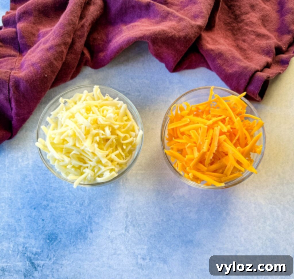 Separate glass bowls of grated mozzarella and grated cheddar cheese, ready for melting