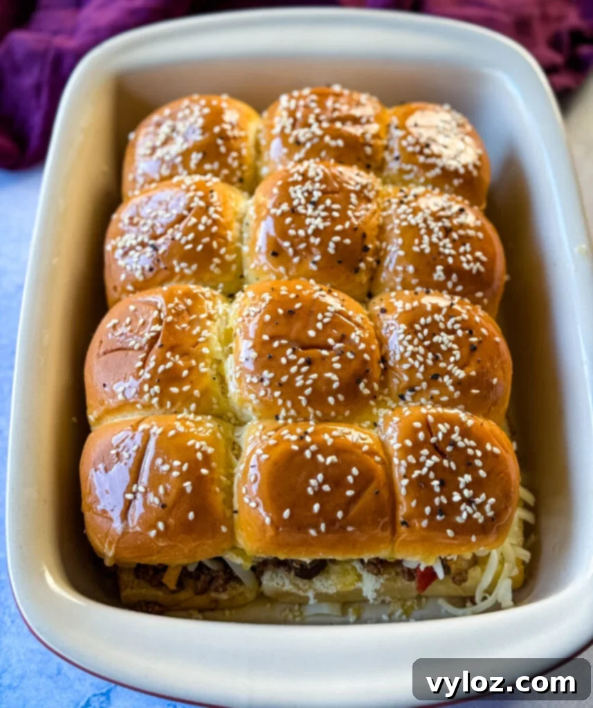 Freshly baked Kings Hawaiian Sliders with golden-brown tops and melted cheese in a vibrant red baking dish