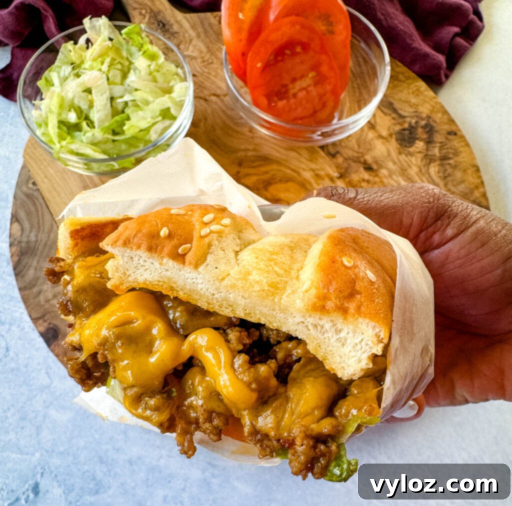 person holding chopped cheese sandwich with lettuce and tomatoes